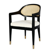 Ylva Dining Chair featuring black rubberwood frame, natural rattan back, white cotton-polyester bouclé seat with silk underlay, foam padding, and brass gold-capped legs for classic comfort and elegance.